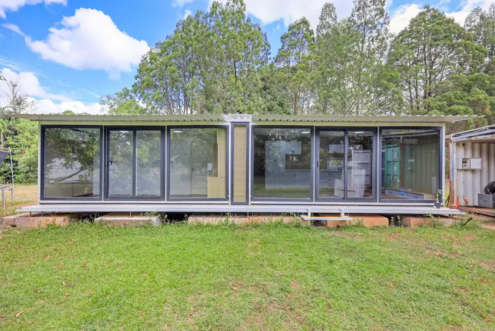 40ft Containerised Slide Out Home opened out, full glass frontage onto lawn