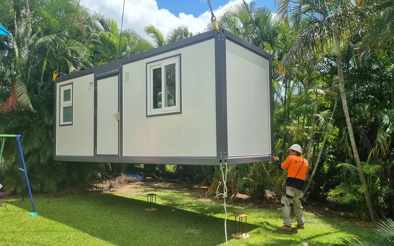 The unit a metre above the lawn with its steel footings set out beneath it, a worker in hi-vis steadying it by hand